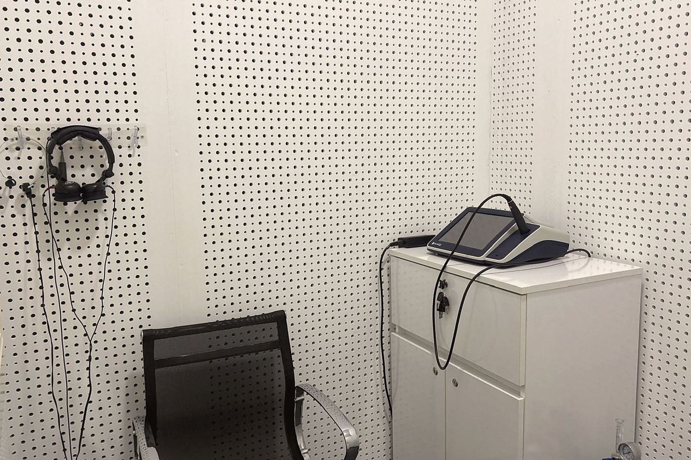 Inside the audiometry booth: headphones on the wall and a portable measuring device on the cabinet